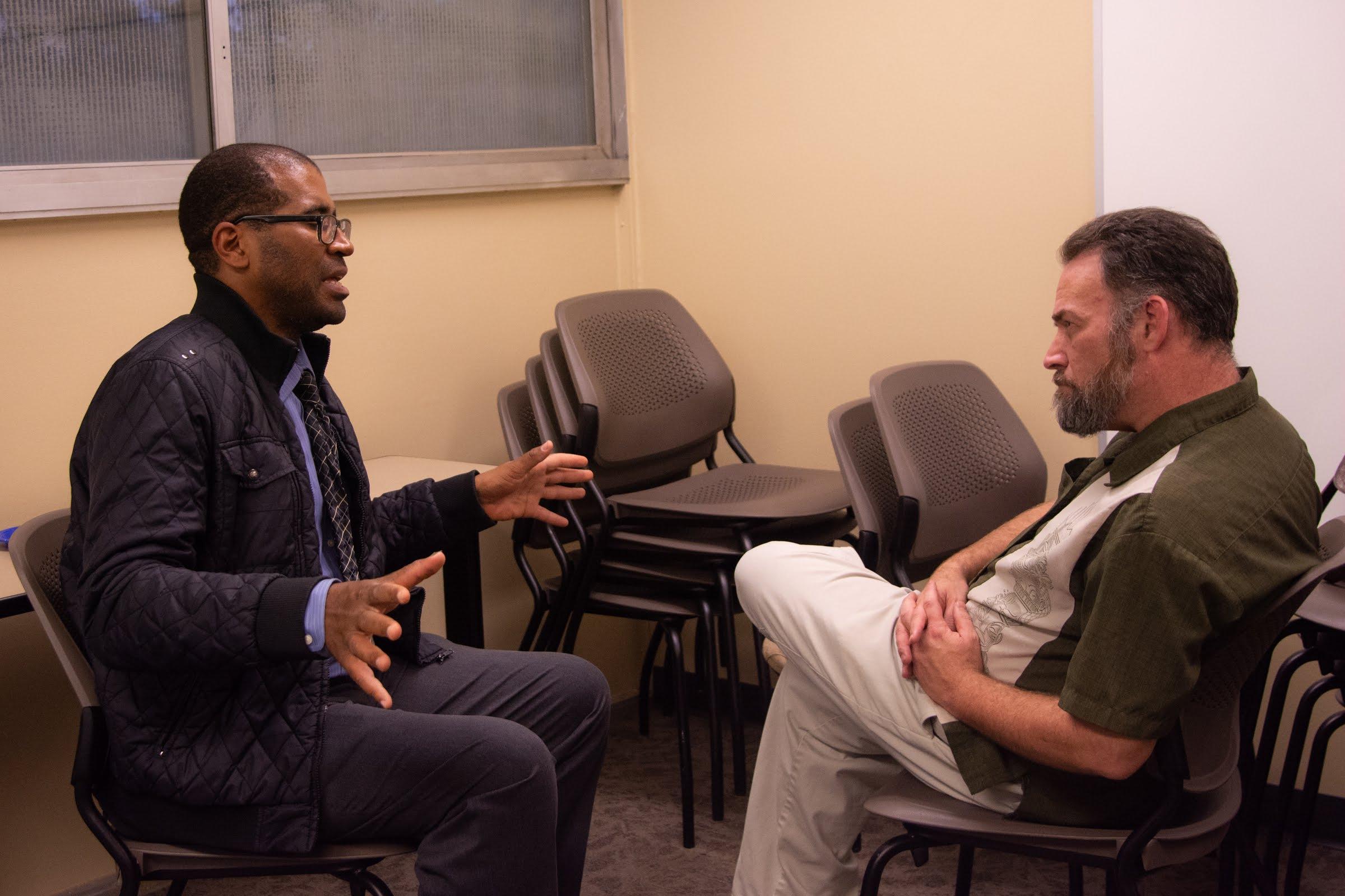 A professor actively listening to a student speak.