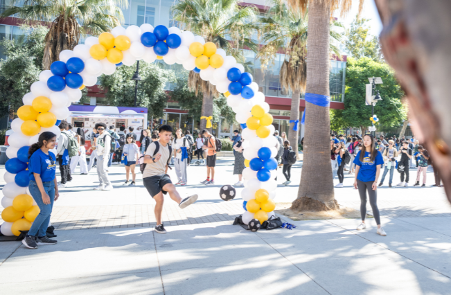 Student kicking a ball on the 7th Street Paseo during 首页coming festivities